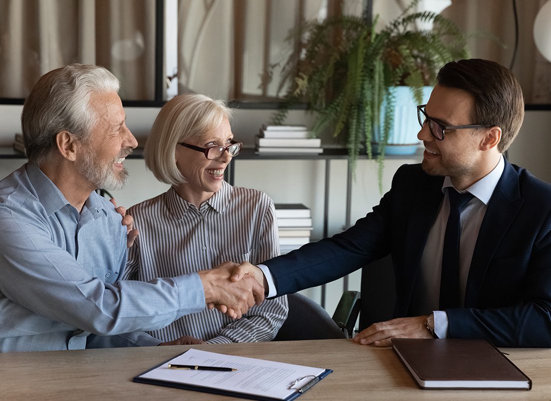 Insurance Solutions - Insurance Agent and Elderly Couple Shaking Hands at an Office
